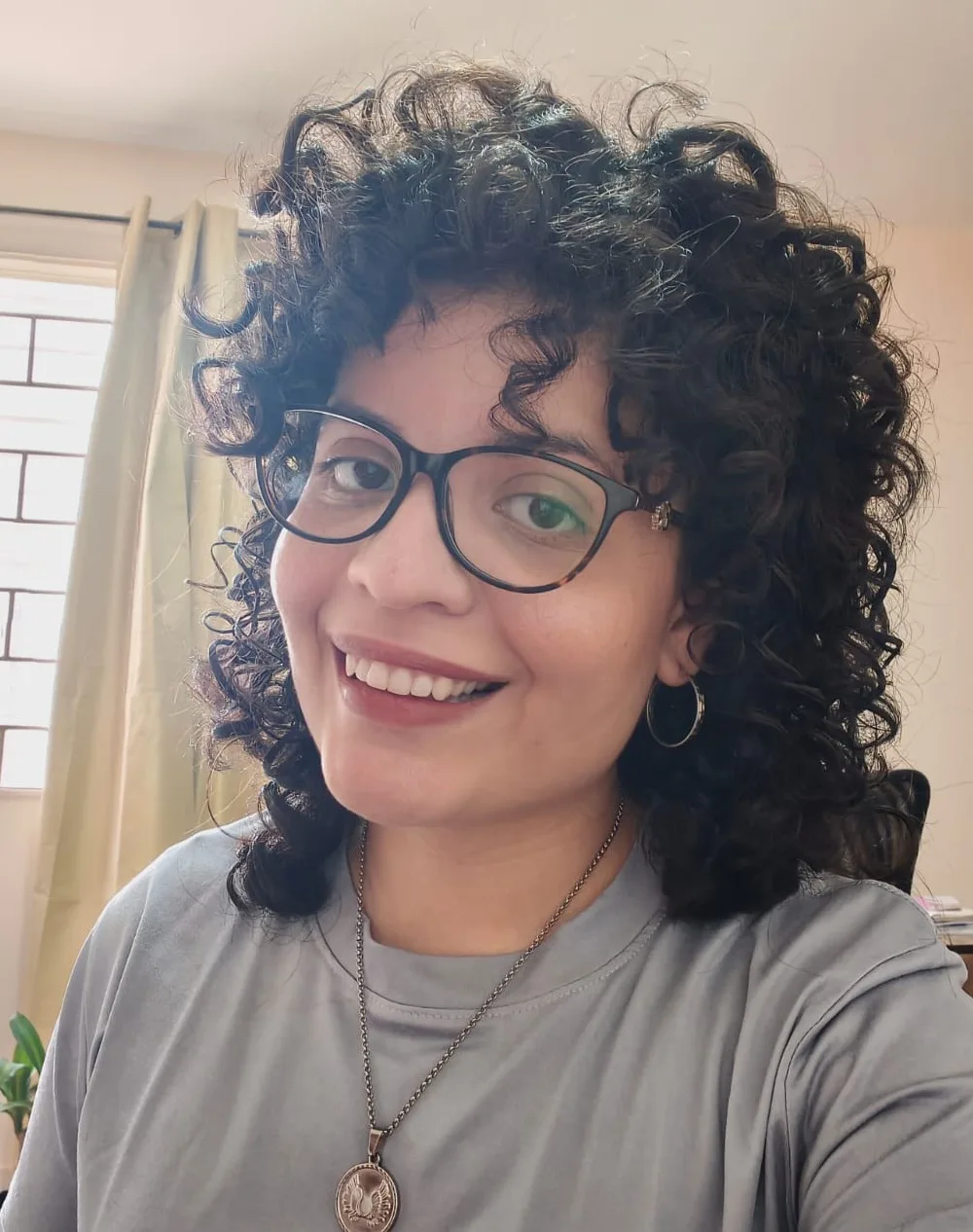 Retrato de Laimary Linares sonriendo, con lentes y cabello rizado